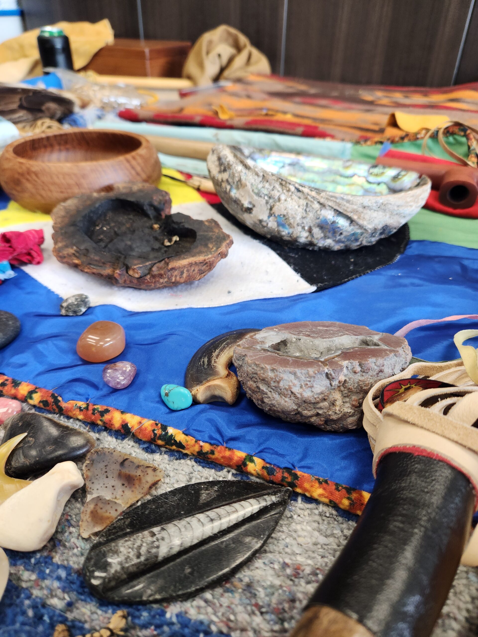 Collection of traditional Indigenous medicines, stones, and ceremonial items displayed on a colorful cloth.